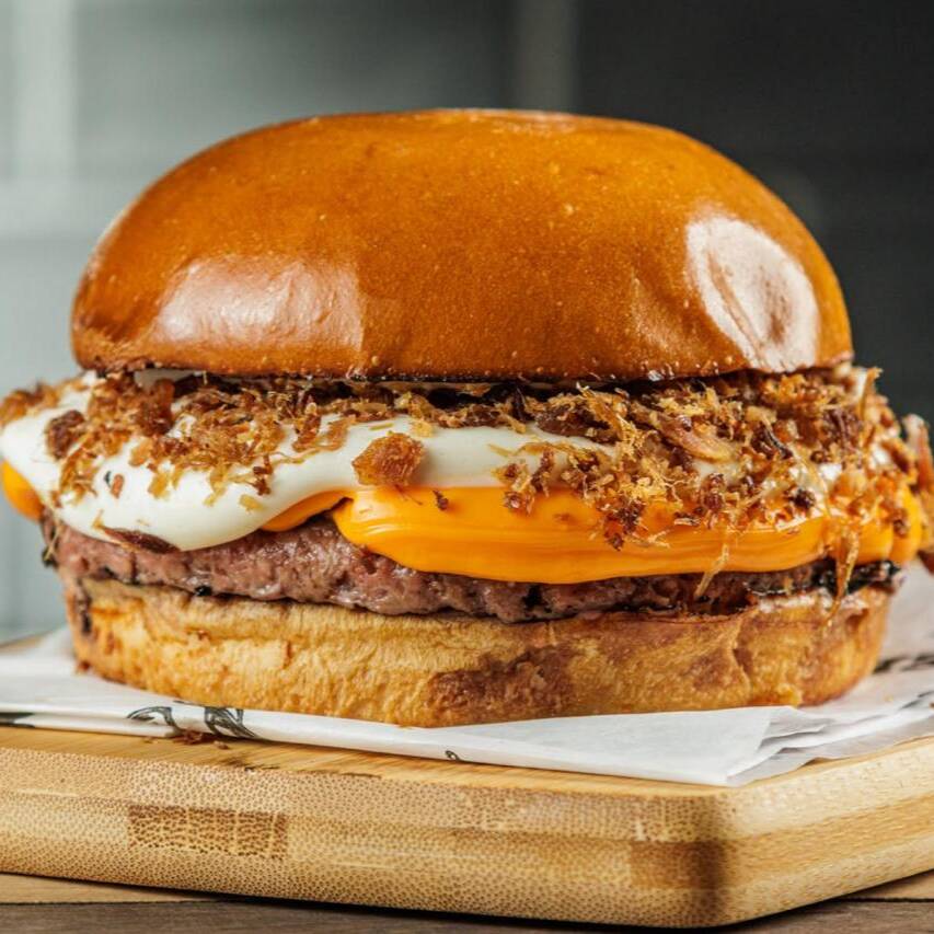 Pão brioche, burger 130g, cheddar cremosão, farofa de bacon e maionese Farini.