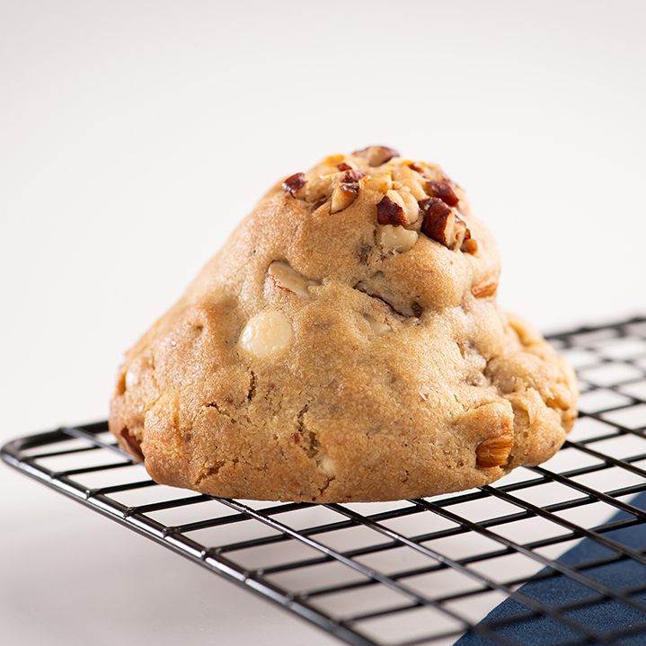 Massa estilo americana úmida por dentro e crocante por fora, gotas de chocolate nobre branco, nozes, amêndoas e noz pecan agridoce.