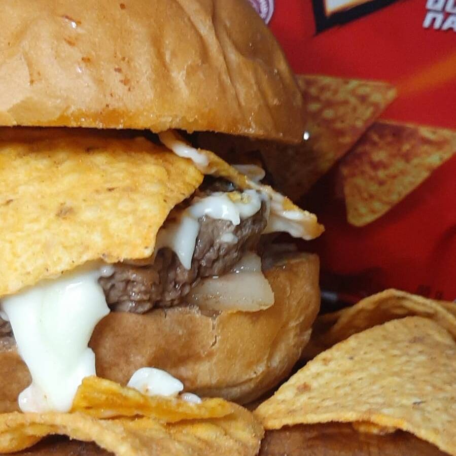 HAMBÚRGUER ARTESANAL DE 180 g, ACOMPANHADO COM QUEIJO DE SUA ESCOLHA, TIRAS DE BACON CROCANTE, SERVIDOS COM CEBOLA ROXA ACOMPANHADO DE DORITOS EM NOSSO DELICIOSO PÃO BRIOCHE PRODUZIDO NA CASA, MAIONESE CASEIRA E BARBECUE.
