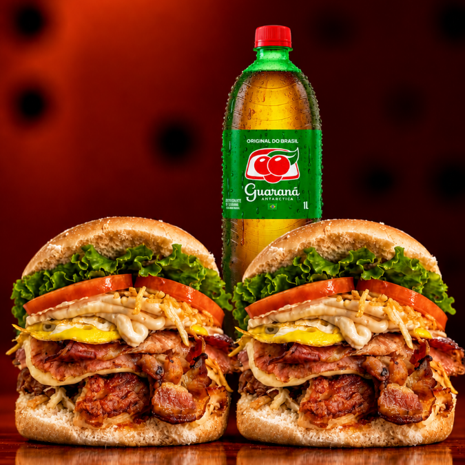 2 X-Tudo Burguer (pão com hambúrguer 100g, queijo, presunto, bacon, ovos, tomate, alface, milho e batata palha), acompanhados de Guaraná 1L grátis. Uma opção reforçada e bem servida.