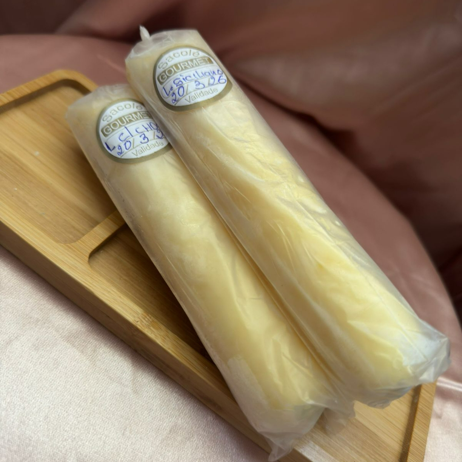 A casquinha fina de chocolate branco cremoso envolve o sacolé como um abraço doce e aveludado, derretendo suavemente ao toque do paladar. Em seguida, surge o recheio de mousse de Limão Siciliano Leve, geladinho e perfeitamente equilibrado, trazendo uma explosão refrescante, cítrica e irresistível.