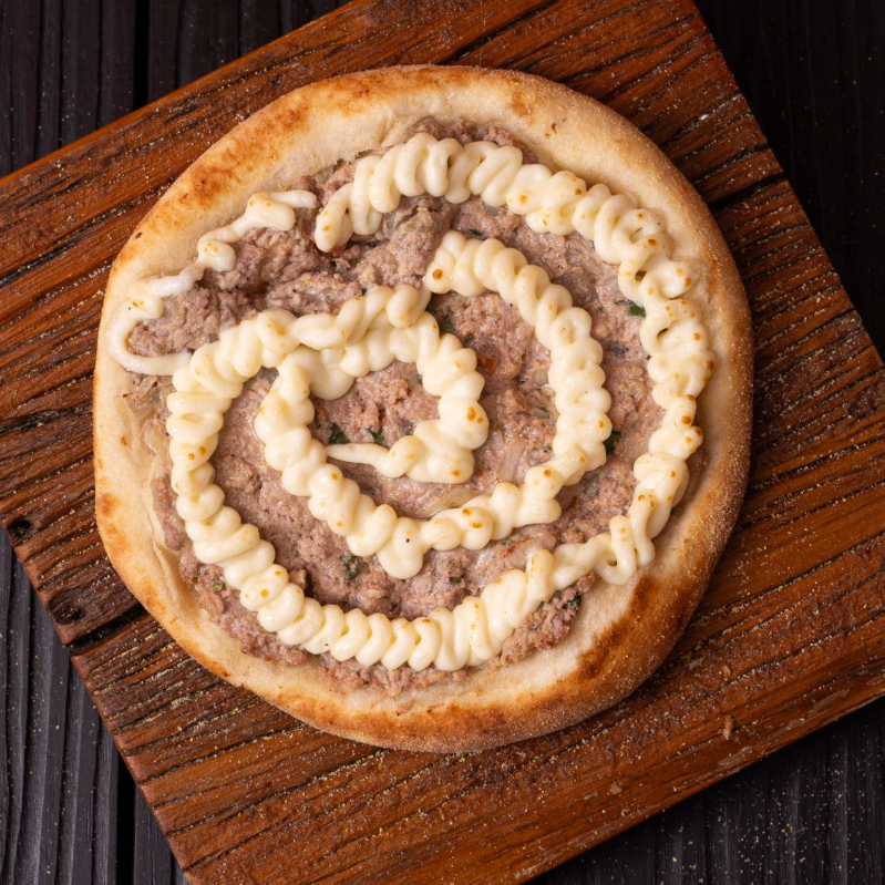 Um clássico coberto com uma espiral de Requeijão. Esfiha de Carne aberta com tomate, cebola e nosso clássico tempero árabe. Finalizada com Requeijão para dar um toque extra de cremosidade.