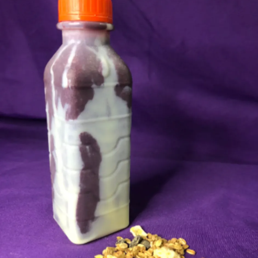 Açaí na garrafa tradicional com camada de leite em pó e leite condensado.