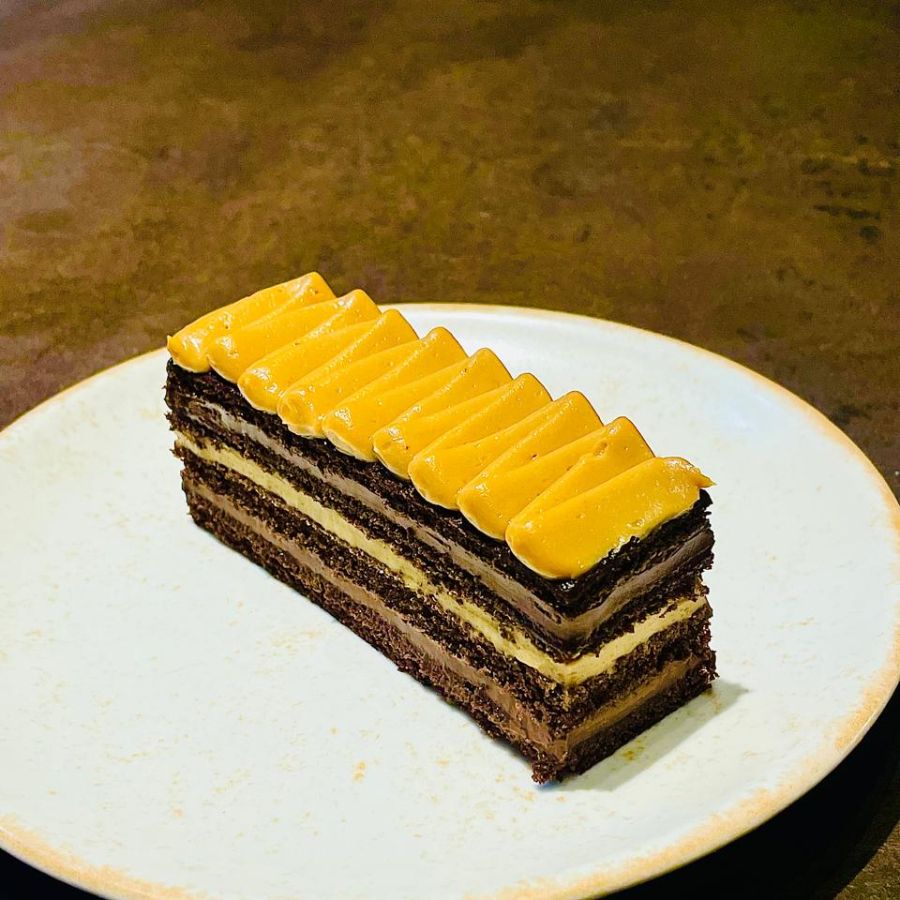Camadas de bolo gelado com mousse de chocolate meio amargo e doce de leite, finalizado com caramelo clássico e crocante salgado.