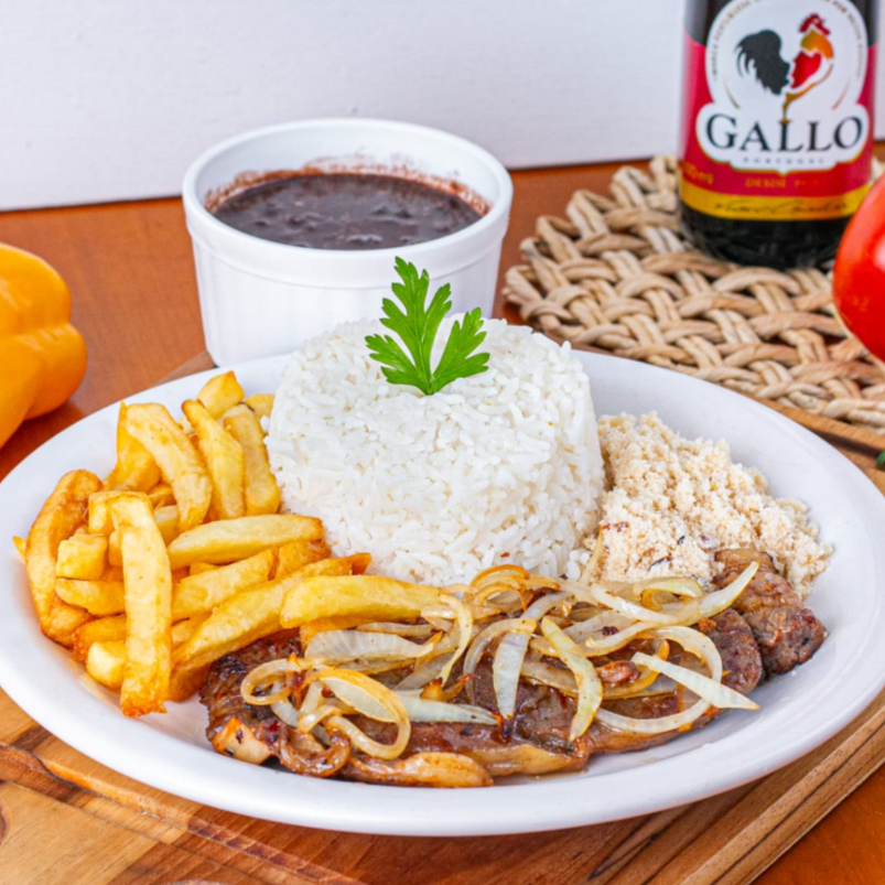 Suculento bife de contra filé acebolado com batata frita. Acompanha um arroz branco soltinho e um feijão preto bem temperado, e nossa tradicional farofa da casa. Servido numa marmitex com aproximadamente 600gr, embalagem vai ao microondas.