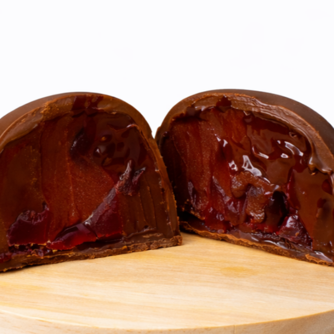 Trufa de cereja feita com ganache de chocolate aveludada e pedaços de cereja, oferecendo o equilíbrio perfeito entre o sabor marcante do chocolate e o toque frutado e levemente da cereja.