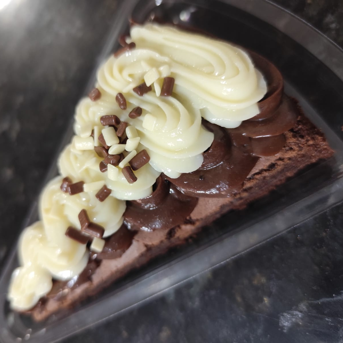 Fatia do nosso brownie com uma massa bem chocolatuda e uma leve casquinha crocante por fora. Generosa cobertura de brigadeiro cremoso de chocolate branco e preto, e finalizado com granulado nobre.