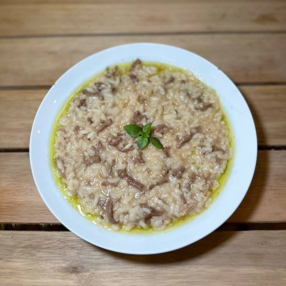 Risoto a base de arroz arbóreo, caldo de carnes e legumes, manteiga e parmesão com fraldinha desfiada. Finalizado com azeite de ervas.