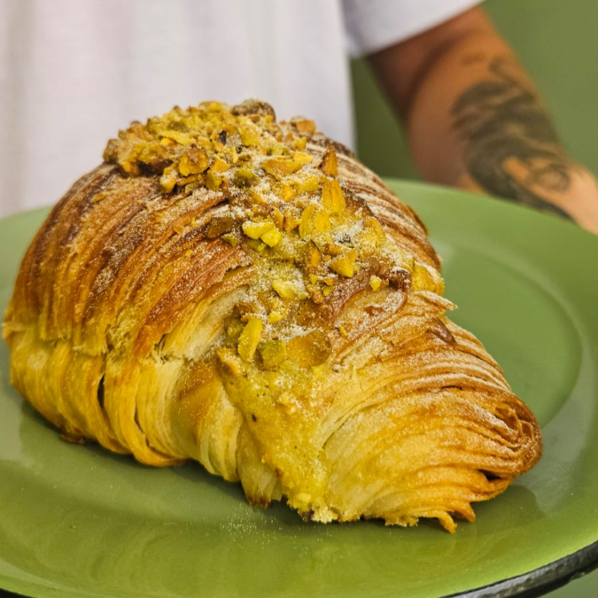 Massa do croissant, recheado de frangipane de pistache, pistache triturado e açúcar de confeiteiro.