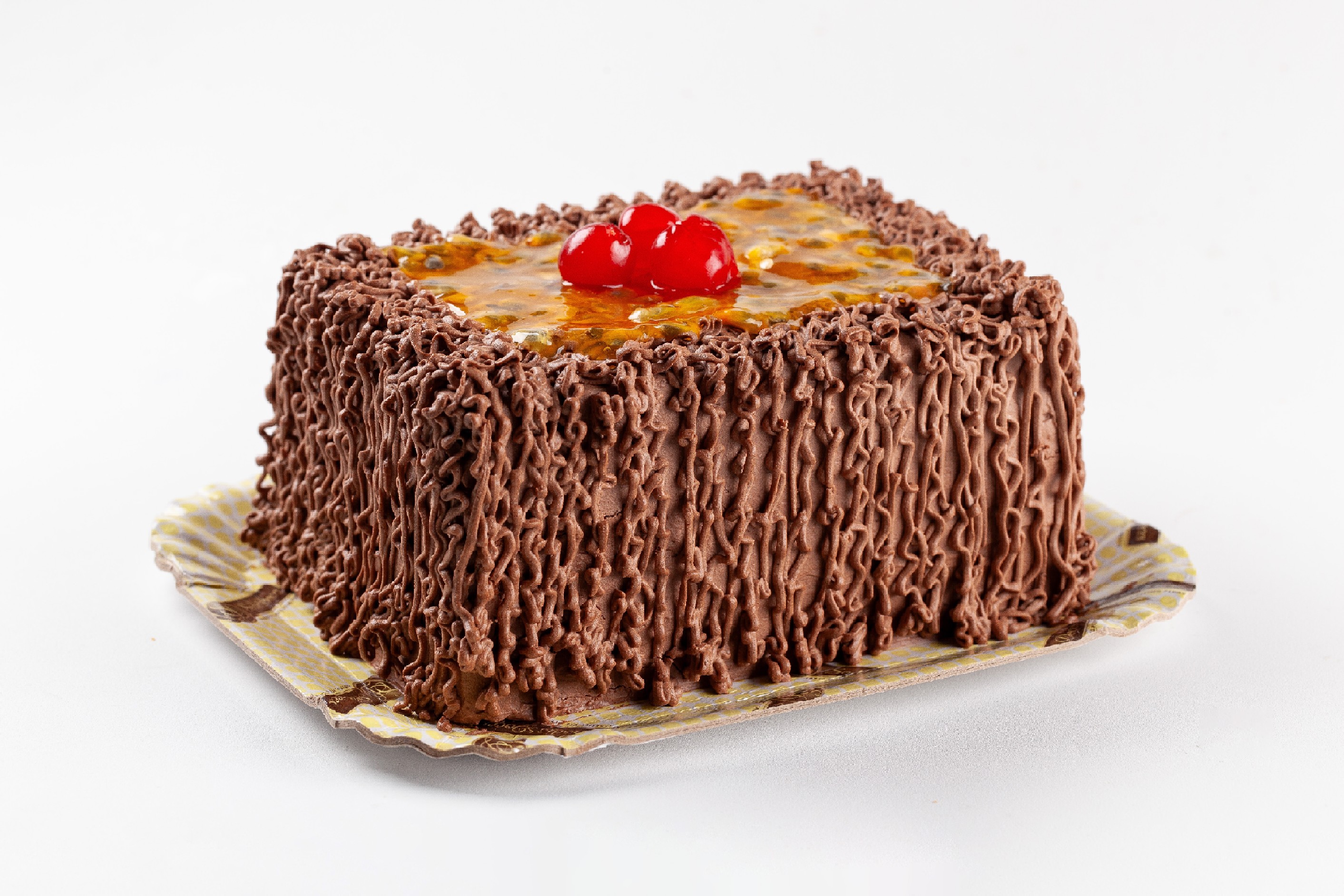 Bolo de massa de chocolate, recheios de mousse de chocolate e mousse de maracujá, cobertura de trufado de chocolate ao leite, polpa de maracujá e cerejas decorativas.