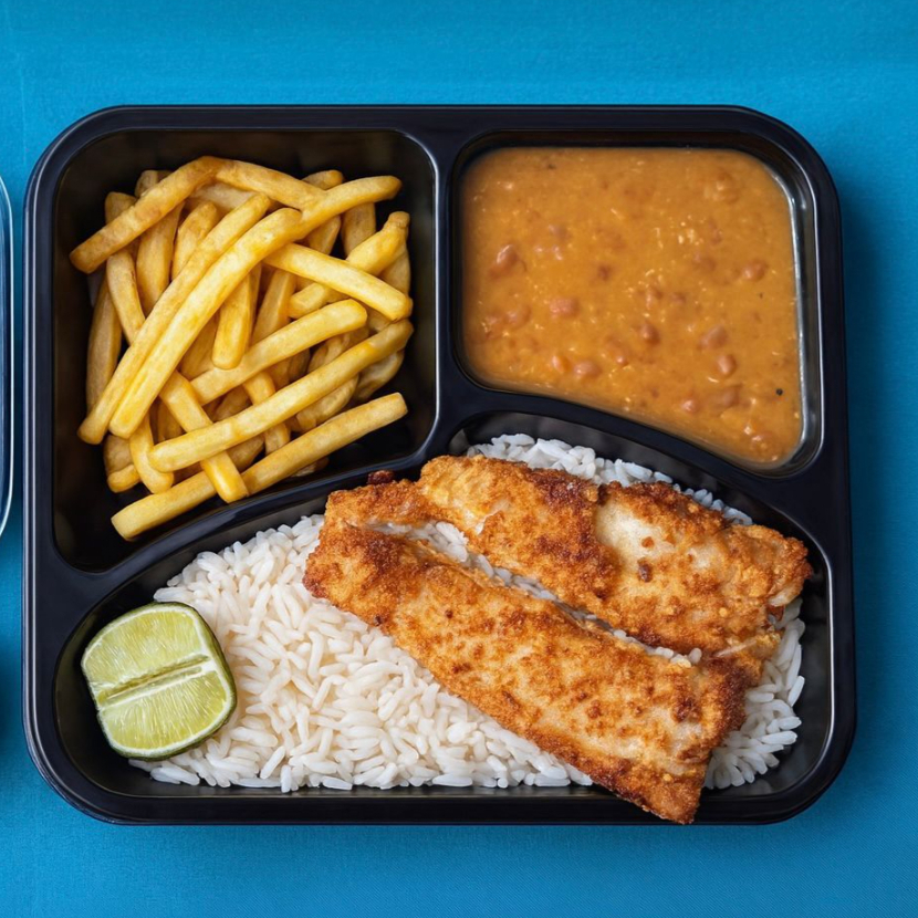 Desfrute da nossa 'Marmitex com Filé de Tilápia Empanada', uma opção irresistível e nutritiva para a sua refeição individual. Este prato é composto por um suculento filé de tilápia, cuidadosamente empanado e frito até a perfeição. Acompanha um arroz soltinho e bem temperado, feijão fresquinho, e uma farofa crocante e saborosa. Para balancear, oferecemos uma salada mista de alface e tomate, regada com um delicioso vinagrete. Como se não bastasse, o prato ainda conta com um macarrão al dente e batatas fritas, crocantes por fora e macias por dentro. Uma combinação perfeita de sabores que irá satisfazer o seu paladar!