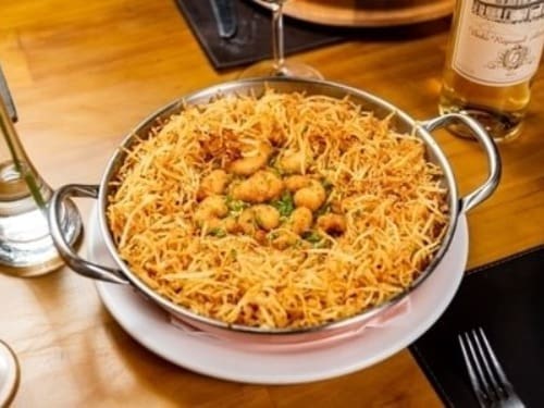 Camarões empanados em farinha panko sobre delicioso arroz cremoso de moqueca. Acompanha batata palha.