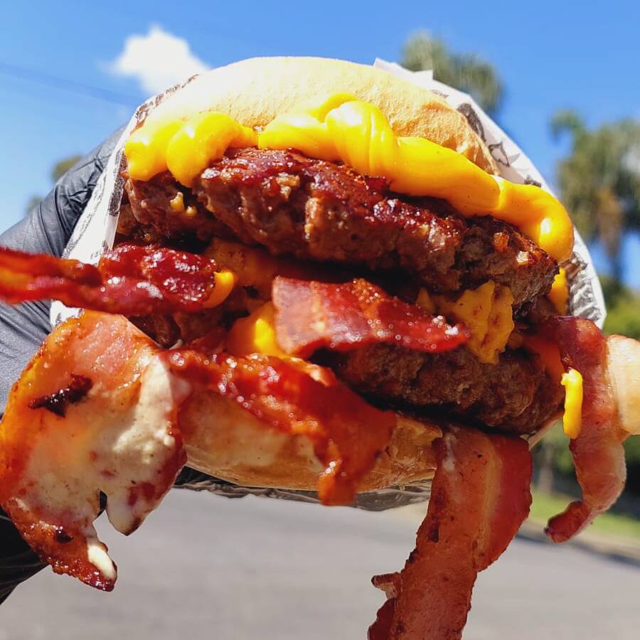 DOIS HAMBÚRGUERES ARTESANAIS DE 180 g, COM DUPLO ACOMPANHAMENTO DE BACON CROCANTE E DUPLO CHEDDAR, SERVIDOS NO NOSSO PÃO DE BRIOCHE ARTESANAL E ACOMPANHADO DE MAIONESE CASEIRA.