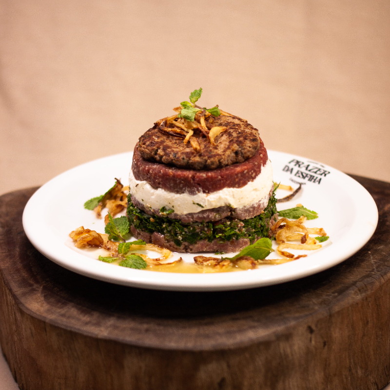 Experiência completa com camadas de kibe cru, coalhada, tabule, kafta e cebola frita crocante.