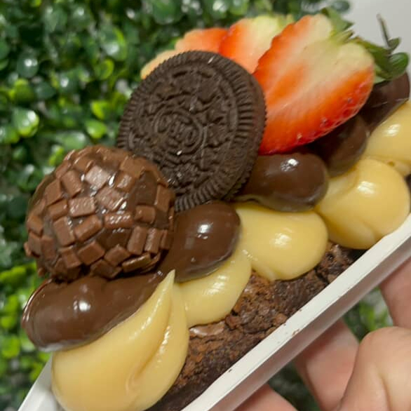 Brownie umido, recheado com brigadeiro 50%, brigadeiro de ninho, morangos frescos, oreo e um docinho de brigadeiro