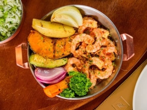 Camarões grelhados, salpicados com alho frito e salsinha no azeite de oliva. Acompanha arroz com brócolis e legumes salteados na manteiga de ervas.