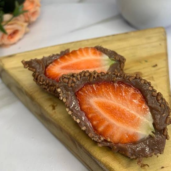 Morango envolvido no brigadeiro tradicional, passado no granulado.