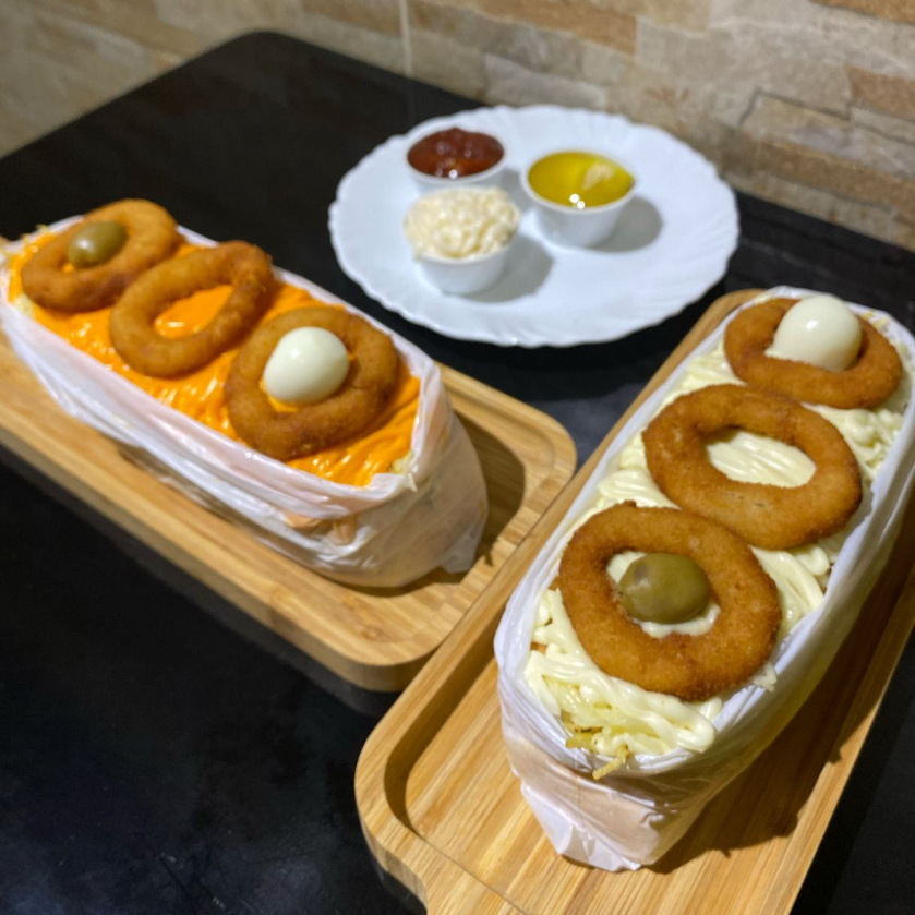 Acompanha: Pão, Salsicha ou Linguiça, Molho, Milho, Ervilha, Molho da Casa, Batata Palha, Cheddar ou Catupiry, Queijo Mussarela Gratinada, Anéis de Cebola e Ovo de Codorna.