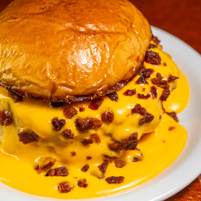 Blend suculento de 180g preparado na brasa, com sabor intenso e ponto perfeito. Finalizado com creme de cheddar cremoso e farofa de bacon crocante que traz textura e potência ao conjunto. Servido no pão brioche premium levemente tostado, macio por dentro e dourado por fora.