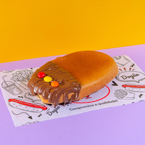 Pao De Dog Tradicional, Recheado Com Creme De Avelã, Leite Condensado e (pedaços de chocolate ao leite recobertos por uma camada de açúcar).