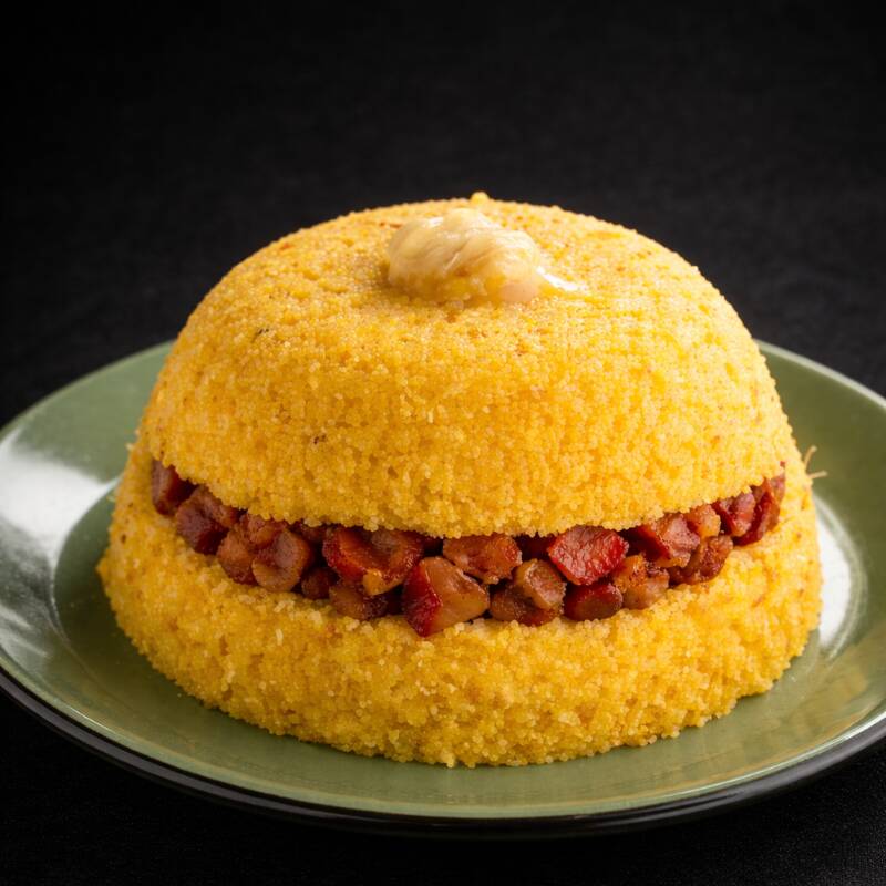 Cuscuz fofinho com bacon crocante, cubos de queijo coalho e cheiro verde.