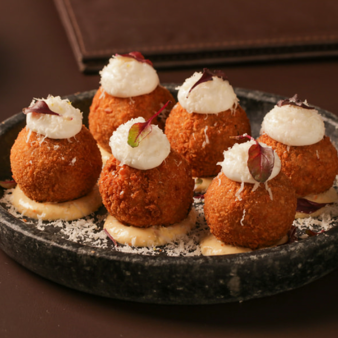 Bolinhos de carne de sol desfiada, queijo coalho, aioli de leite, parmesão ralado, molho tártaro e broto.