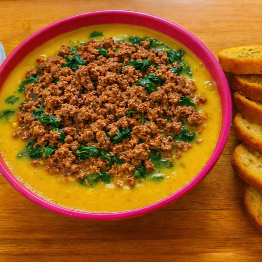 Caldo de mandioquinha com carne moída, cebolinha e torradas temperadas.