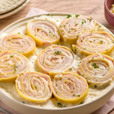 Rondelli de Presunto e Queijo com Molho Branco. Massa leve e fresquinha, recheada com presunto e queijo derretido, coberta com um delicioso molho branco cremoso. Uma combinação perfeita de sabor e textura, feita com carinho e ingredientes de qualidade!