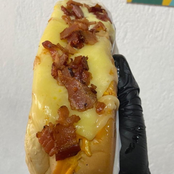 Pão de Dog com 2 salsichas, maionese, vinagrete, batata palha, pure, milho, ervilha, maionese temperada especialidade da casa, cheddar, requeijão e bacon.