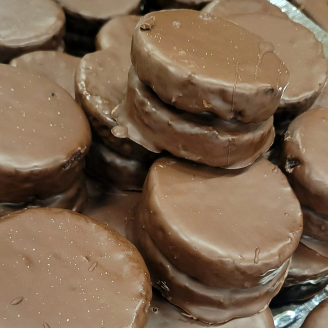 Massa macia com mel e especiarias, cobertura de chocolate e recheio de doce de leite.