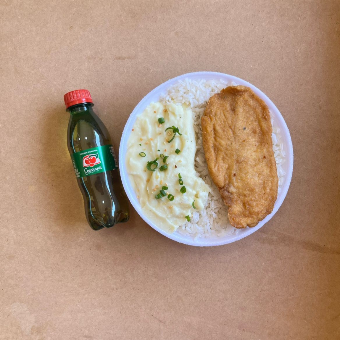 Marmita com delicioso filé de frango empanado na massa crocante acompanhado de arroz branco, feijão e purê de batatas inglesas. Acompanha refrigerante pet Guaraná Antárctica bem gelado. Marmita indicada para 01 pessoa.