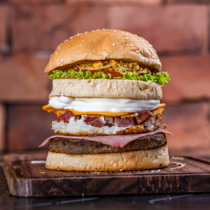 Pão, hambúrguer picanha 120gr, ovo, bacon em cubos, presunto, queijo, Catupiry ou Cheddar, milho verde, batata palha, alface e tomate
