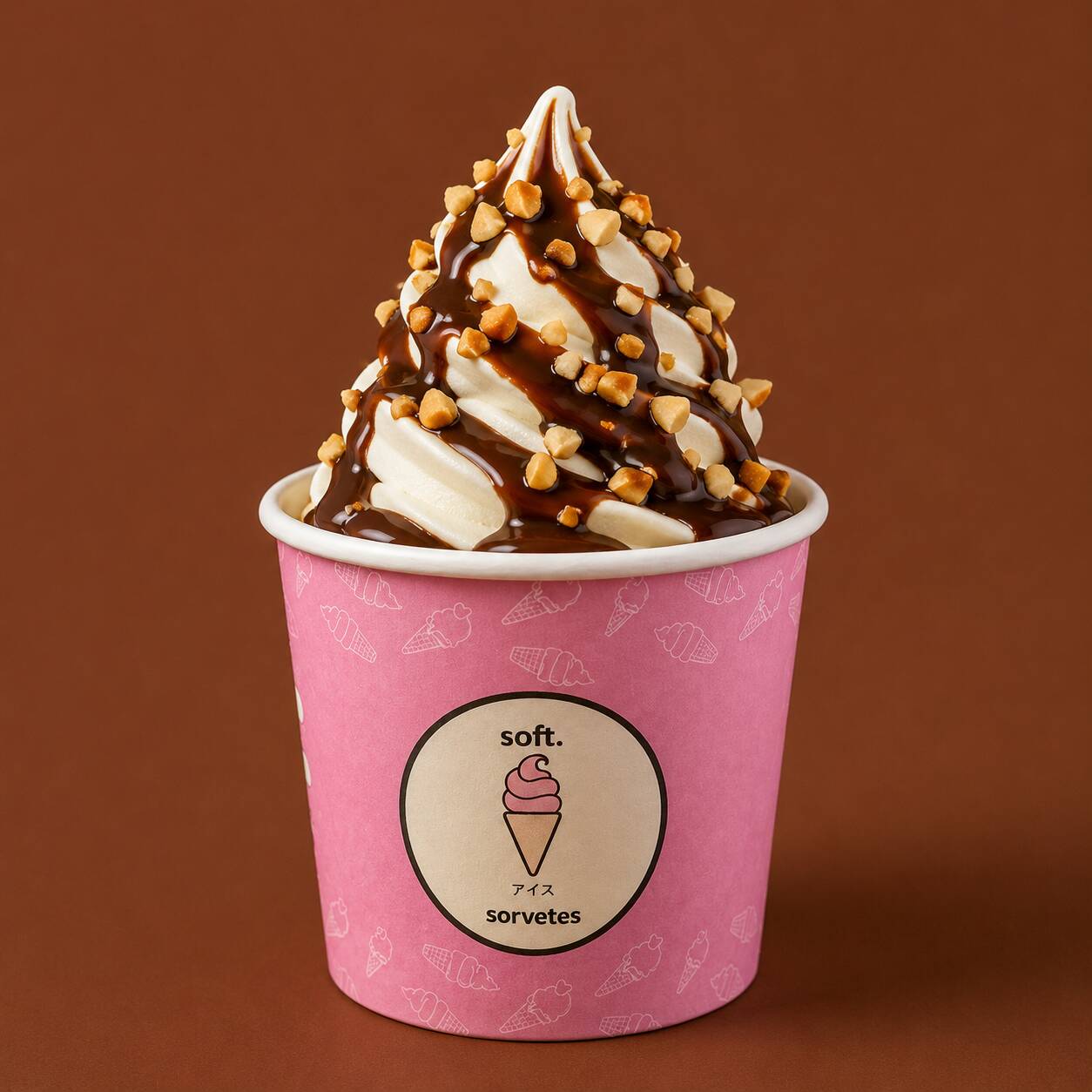 A elegância do chocolate em sua forma mais refrescante. Nosso Sundae Cioccolato combina o sorvete de baunilha soft com uma intensa calda de chocolate belga, rica e aveludada, que envolve cada colherada com sabor profundo e marcante. Acompanha Amendoins Crocantes e um Canudo Biju. imagem ilustrativa.