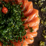 Fatias de barriga de salmão temperadas com molho especial a base de azeite trufado com crispy de couve.