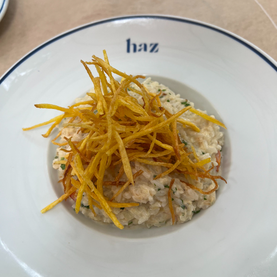 Arroz de jasmin cremoso com lascas de bacalhau, tomatinhos confit, azeitona preta e coberto com palha crocante de baroa