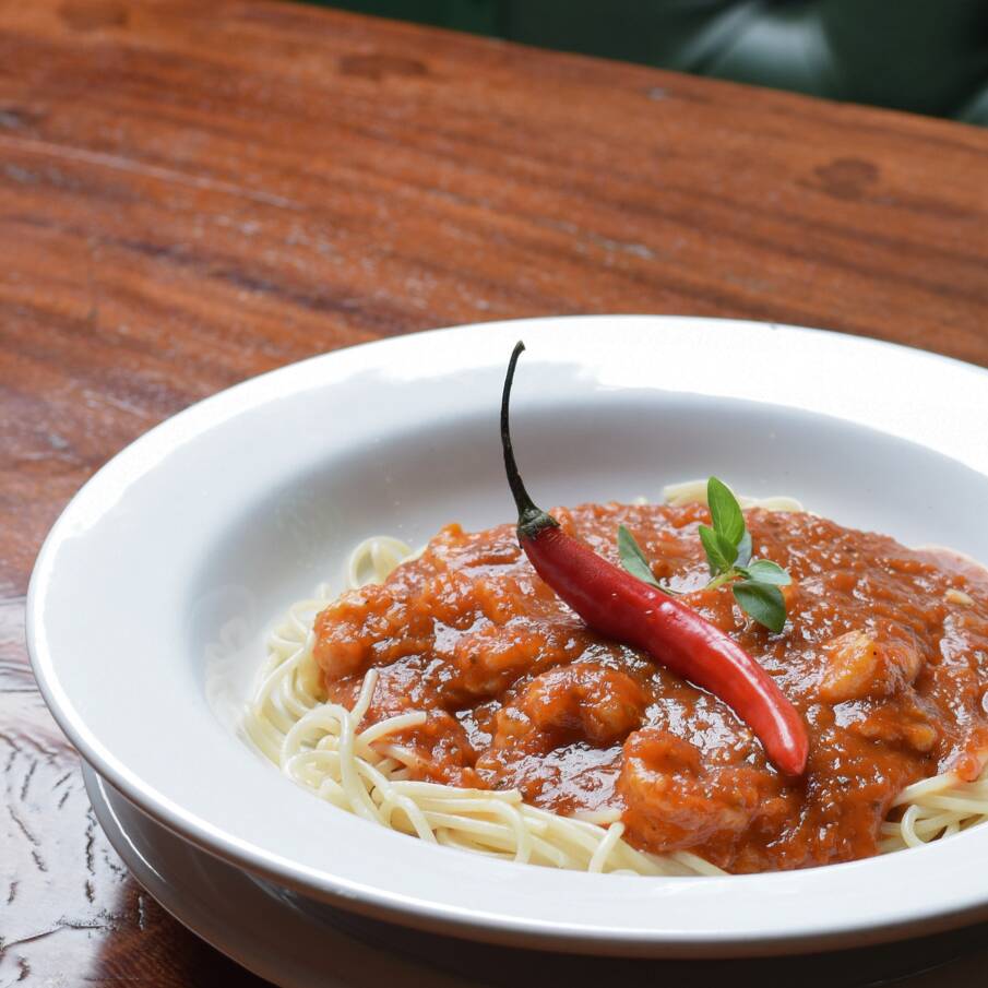 Espaguete com laminas de alho e manjericão no azeite, servido sobre molho de tomates frescos e parmesão.