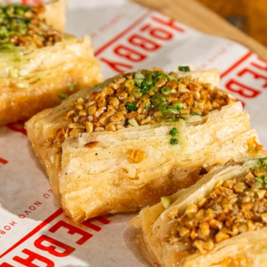 Baklava tradicional, feita com camadas de massa folhada crocante, recheada com nozes trituradas e regada com mel.