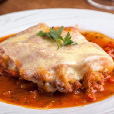 Filé bovino empanado regado ao molho de tomate, gratinado com mussarela e orégano, acompanhado de espaguete e batata frita.