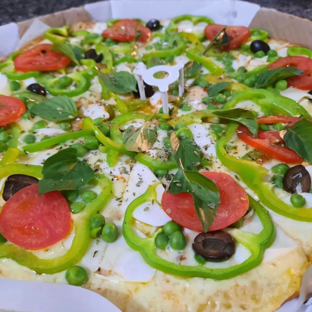 Massa, molho, muçarela, pimentão, tomate, azeitonas, ervilha, orégano e manjericão.