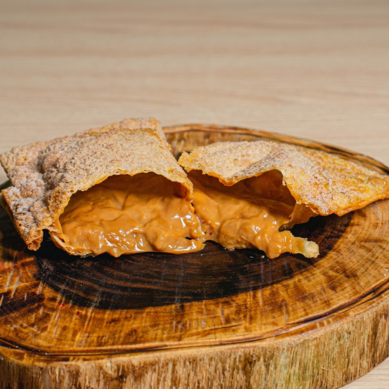 Pastel crocante recheado com doce de leite cremoso, frito até dourar e finalizado com açúcar e canela.