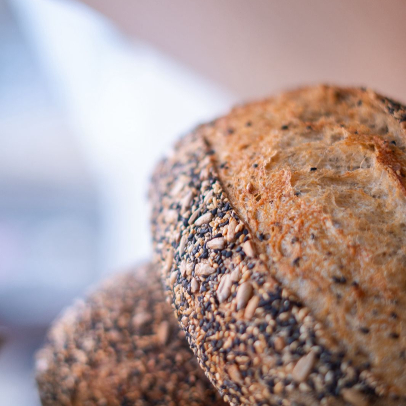 Nosso pão multigrãos é feito com fermentação natural e massa semi integral, garantindo leveza e sabor. Leva sementes de girassol, chia e gergelim preto e branco misturadas na massa e salpicadas por fora, criando crocância na casca e uma textura rica no interior. Nutritivo, saboroso e feito com tempo e cuidado.