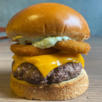 Pão, hamburguer de fraldinha 120gr, queijo cheddar, cebolas empanadas e maionese verde.