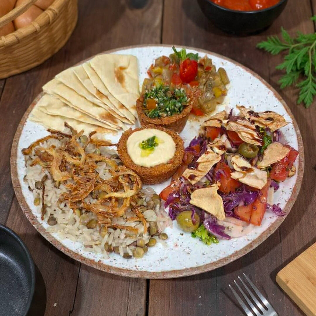 Arroz com lentilha, acompanha cebola frita, Salada de berinjela, 2 unidades de falafel aberto recheados de tabule e pasta de grão de bico, salada Fatuche e pão sírio.