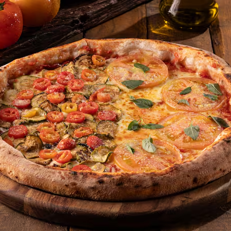 Pizza grande, requintada e de dois sabores de Pizza distintos irá encantar o seu paladar. Uma metade é dedicada à clássica Pizza de Margherita, ornamentada com mozzarella fresca, tomates suculentos e um toque de manjericão, que a torna uma verdadeira celebração de sabores italianos tradicionais. A outra metade de Pizza apresenta a sofisticação da Zucchine Gratinate Al Parmigiano, uma combinação de abobrinha delicadamente gratinada e parmesão, proporcionando uma experiência gastronômica única. Desfrute deste manjar em 8 pedaços de Pizza generosos. Uma delícia para todos os amantes de pizza, disponível com frete grátis durante a promoção do mês da pizza na nossa loja! Pizza a opção perfeita para duas pessoas, nada como uma Pizza para comemorar datas especiais como Dia dos Namorados, Festa Junina e muito mais, com quem vai dividir sua Pizza hoje.