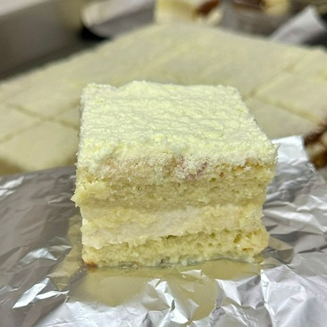 Massa amanteigada bem molhada, recheada com mousse de ninho, embalado em papel alumínio