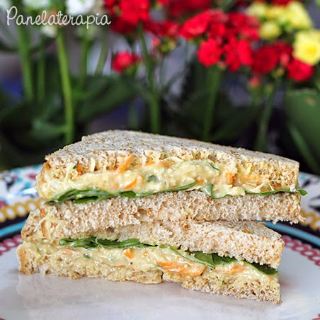 sanduiche feito no pão de caixa integral , recheado com pasta de frango , cenoura ralada , requeijão light e finalizado com folhas de rucúla fresca .