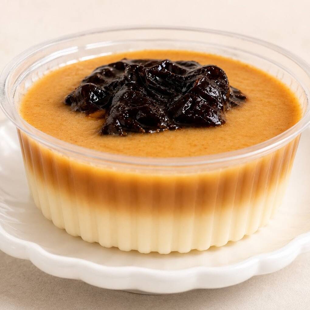 Beijinho de coco cremoso com calda de doce de leite e ameixas.