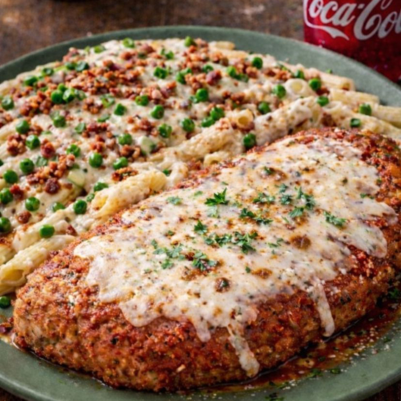 Uma incrível Parmegiana de Frango acompanhada de um irresistível macarrão parisiense, preparado com molho branco cremoso, presunto suculento e ervilha fresca verdinha. Para completar, o prato é finalizado com queijo derretido e um toque especial de cebolinha fresca, garantindo sabor, leveza e aquela apresentação que conquista no primeiro olhar. Ideal para quem busca uma refeição farta, elegante e cheia de sabor!