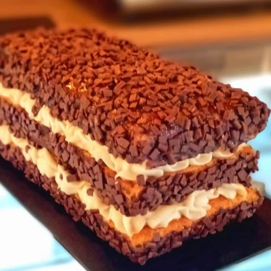 Bolo branco coberto com pedacinhos de chocolate belga (flakes) e recheio de ganache de chocolate branco