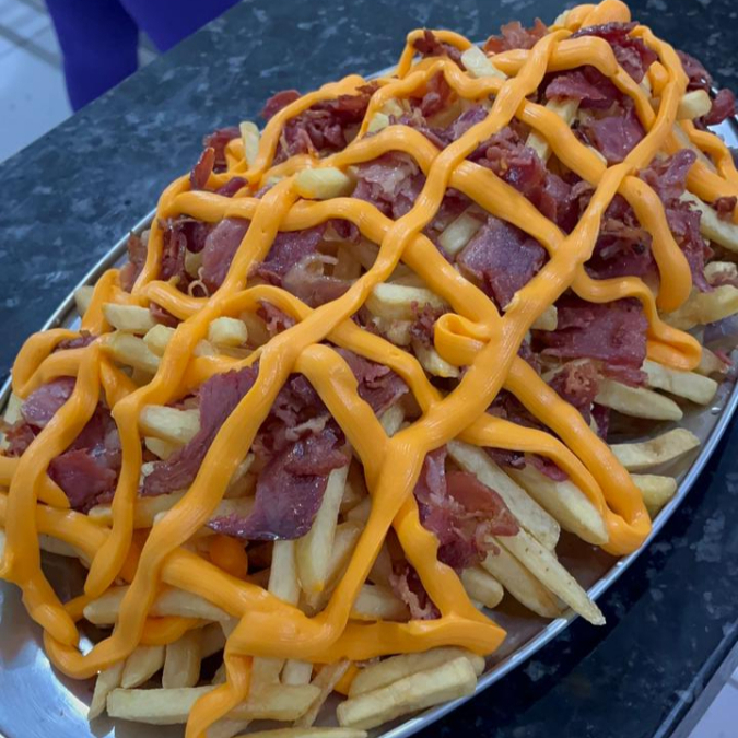Batatas fritas crocantes cobertas com cheddar cremoso e bacon, uma explosão de sabores em cada mordida.